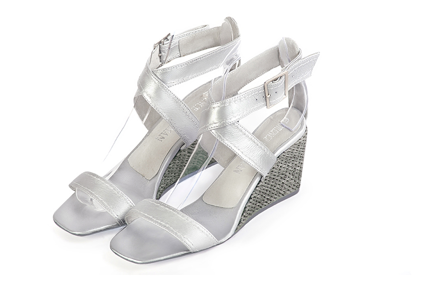 Silver elegant sandals with cross straps across the instep, fully open. Square toe. Medium wedge heels.